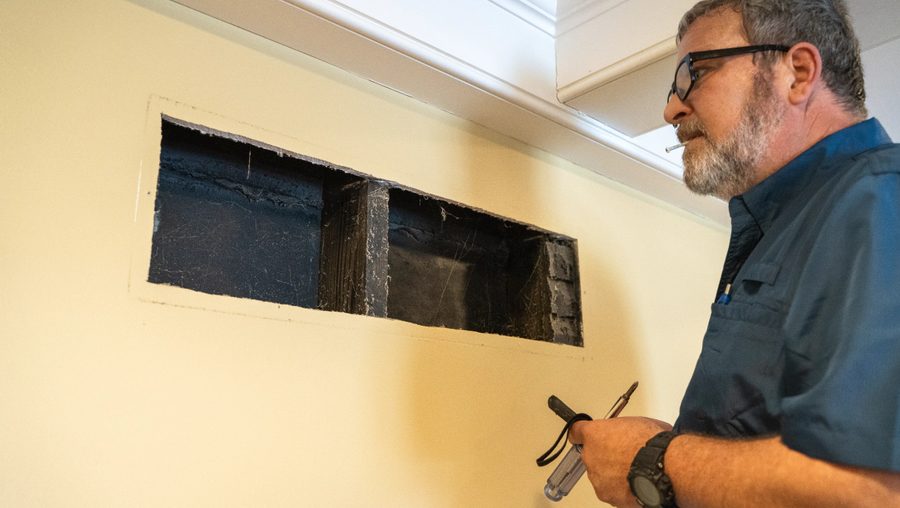 Technician inspecting a wall return during a duct system assessment