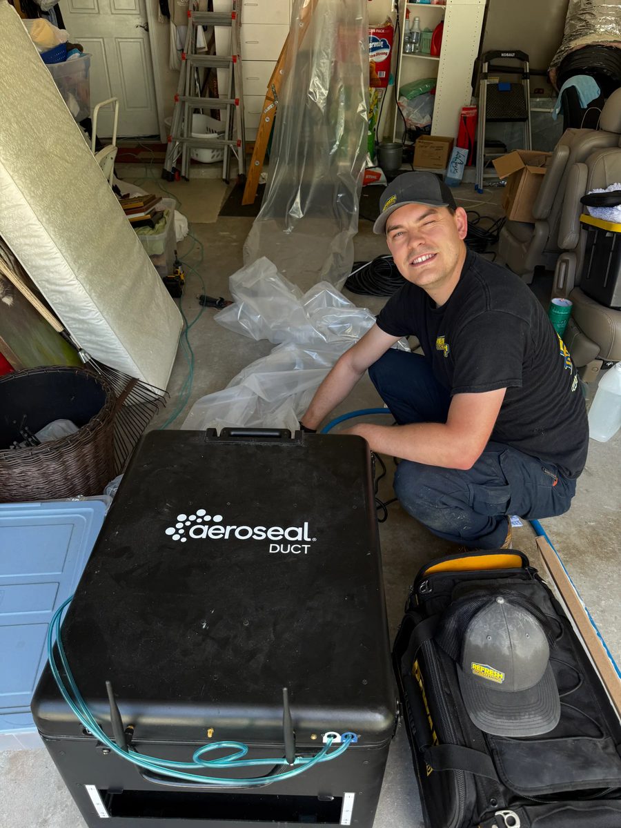 Technician operating Aeroseal duct sealing equipment on a residential system