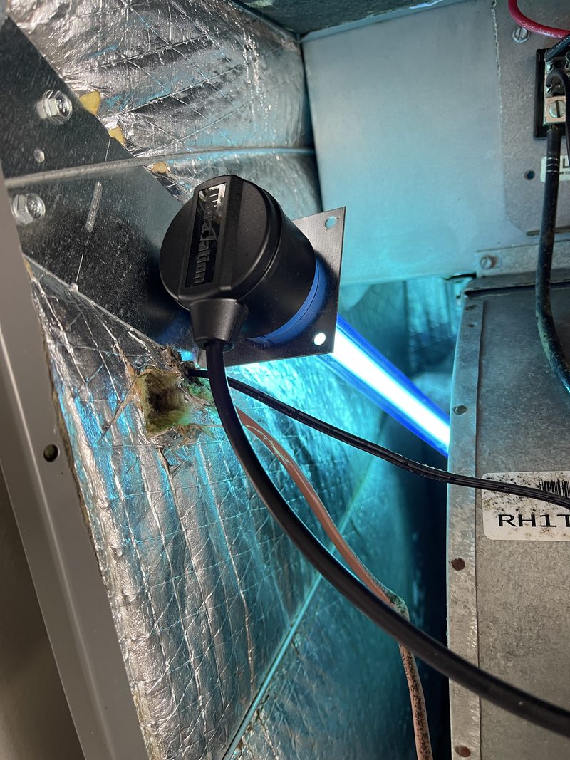 UV-C lamp installed inside an air handler, illuminating the coil compartment