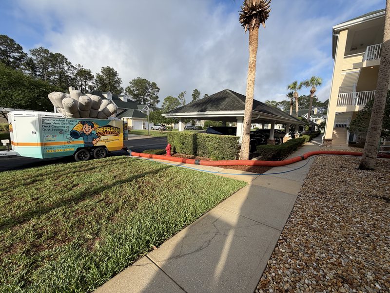 Collection hose routed across a multi-family property during a duct cleaning